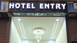 A hotel entry with a metallic elevator, a chandelier, and a signboard above the entrance. - Hotel HR Comfort (Ahmedabad)