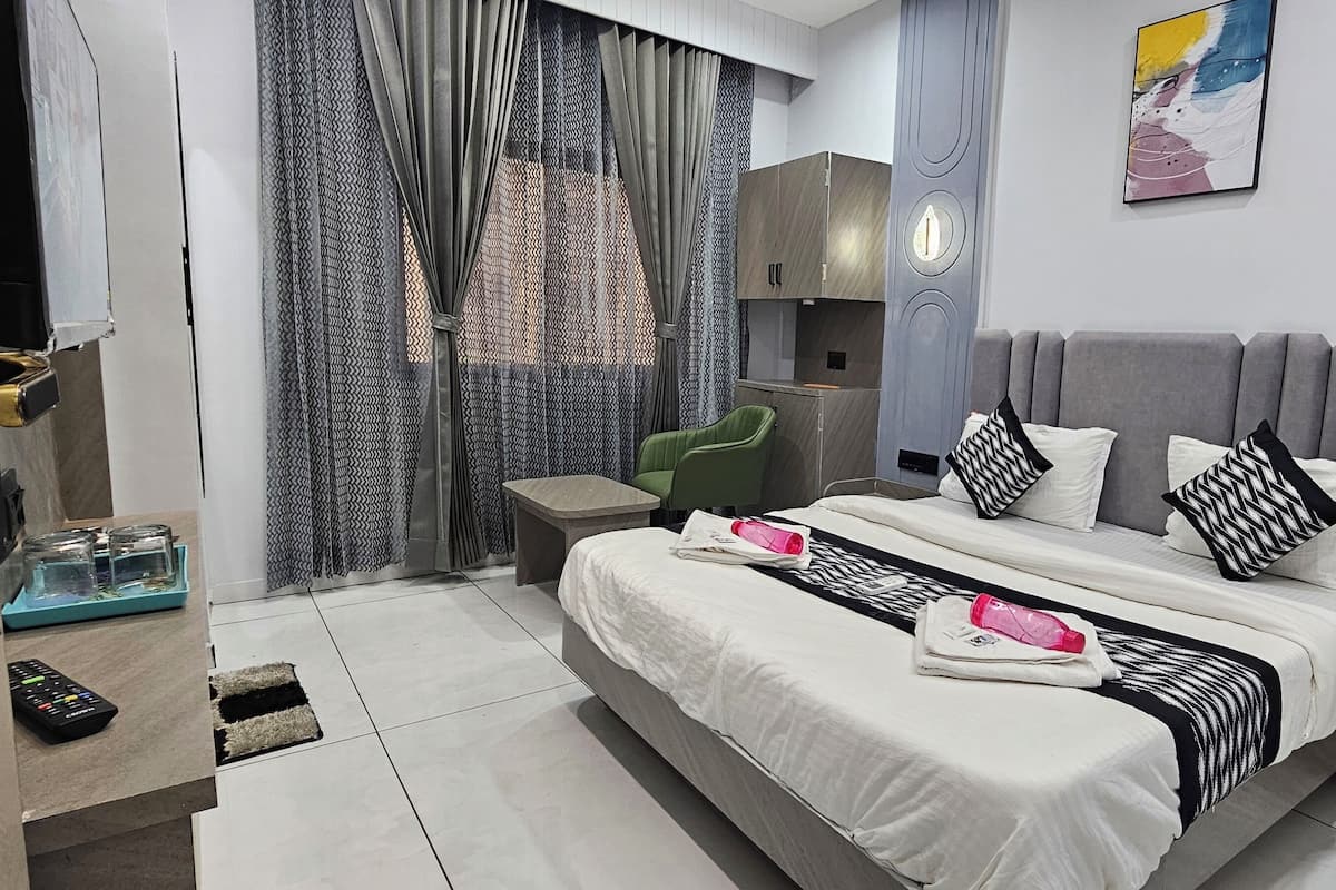 Una habitación de hotel moderna con una cama, un pequeño rincón de estar, un televisor y un cuadro en la pared.