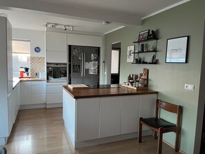 Eine moderne Küche mit weißen Schränken, einer Holz Arbeitsplatte und einer fest eingebauten Kochinsel.