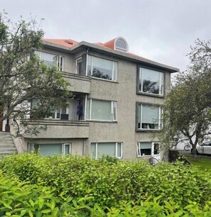 Ein mehrstöckiges Gebäude mit großen Fenstern, einem roten Dach und einem Balkon.