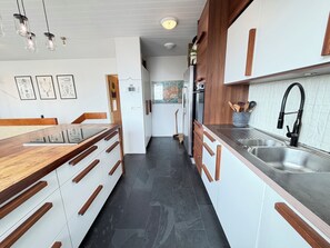 Eine moderne Küche mit Holzausstattung, einer Edelstahlspüle und einem eingebauten Backofen.