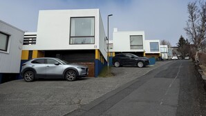 Una zona residenziale moderna con case indipendenti, posti auto numerati e auto parcheggiate.