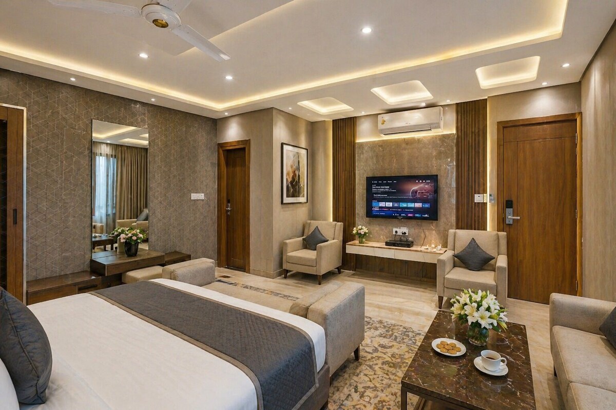 Una moderna camera d'albergo con un letto grande, due poltrone, un divano, una TV e un tavolino da caffè.