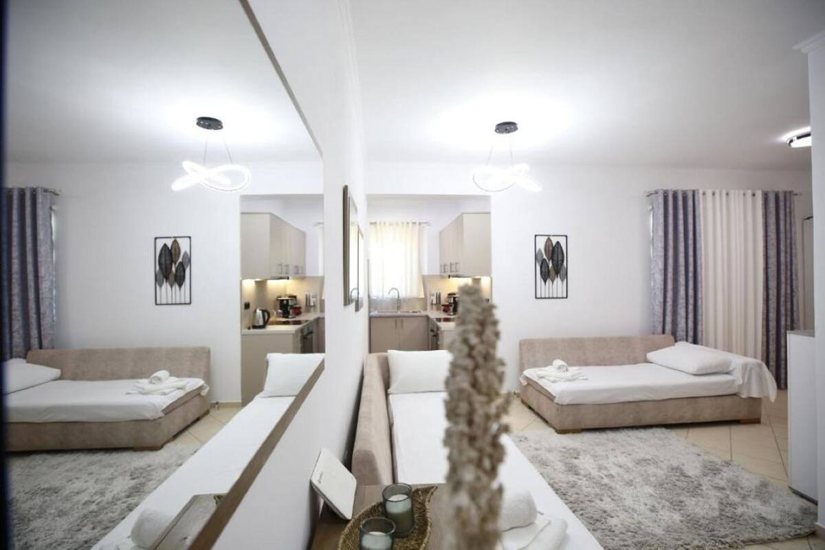 Una habitación de hotel moderna con dos camas, una zona de estar, una cocina y un baño.
