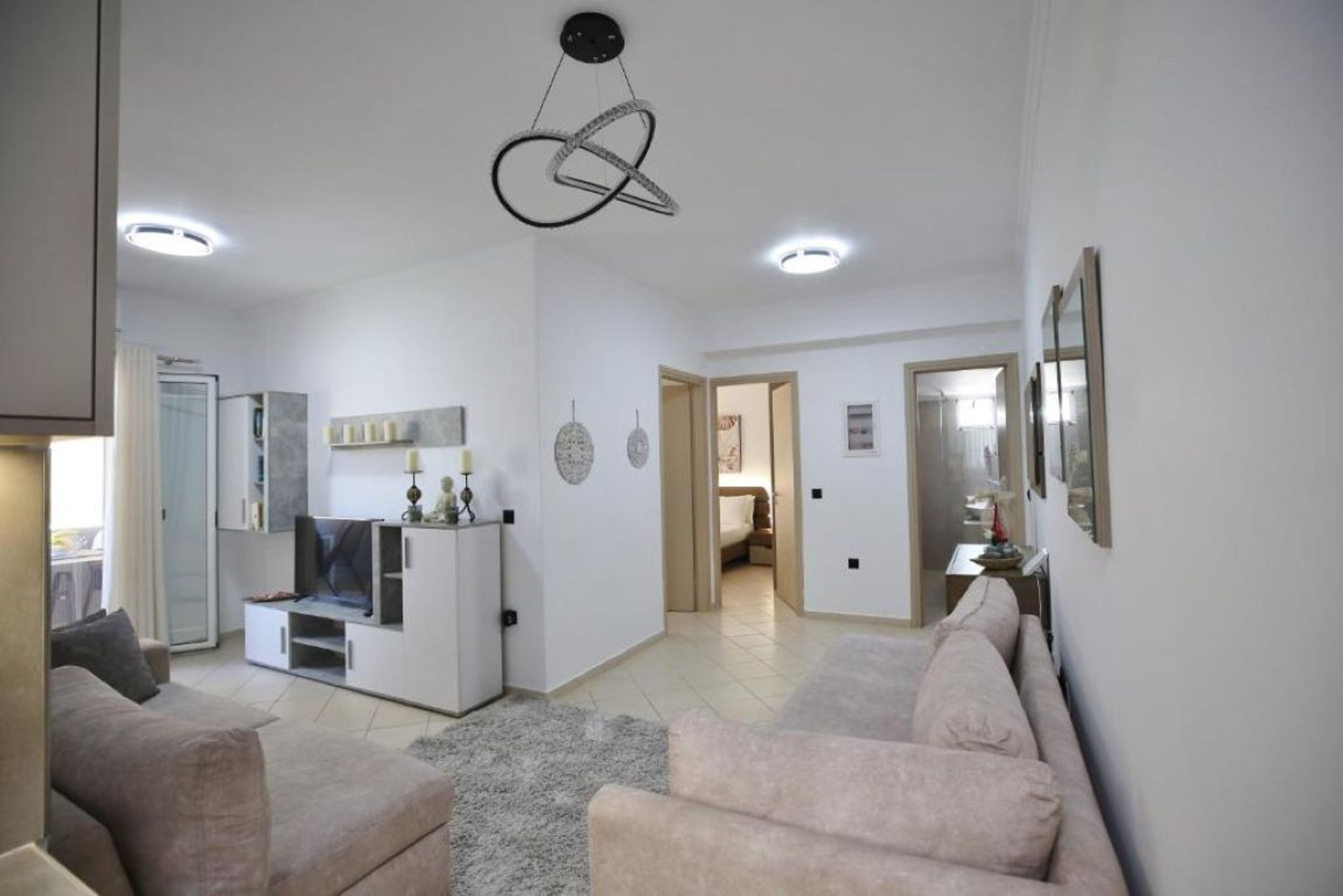 Un vaste espace de vie comprenant un canapé, un téléviseur et un luminaire au plafond au design original.