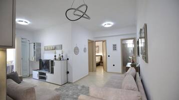 Un vaste espace de vie comprenant un canapé, un téléviseur et un luminaire au plafond au design original.