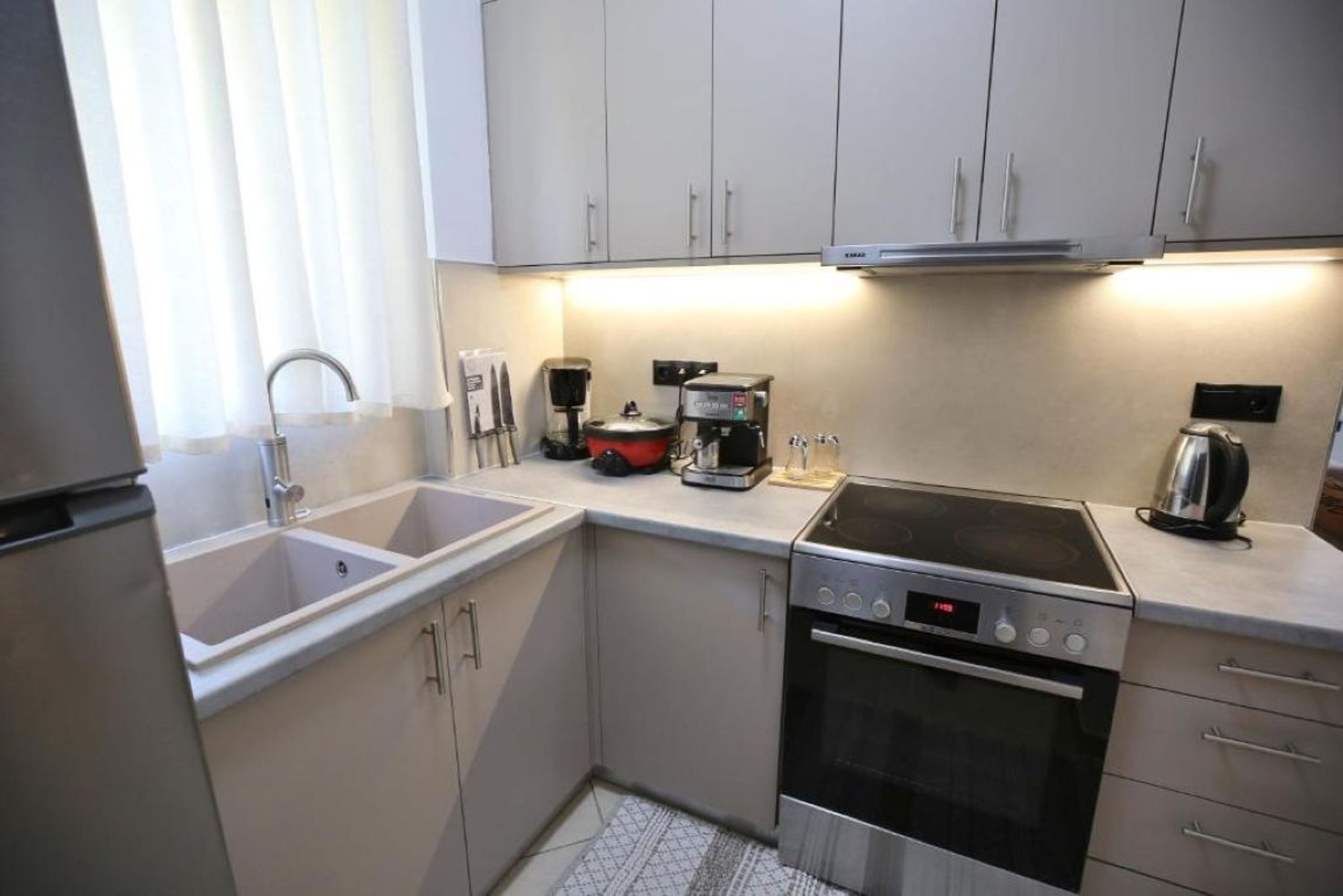 A compact kitchen with a sink, stove, and coffee maker.