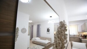 A modern, well-lit bedroom with a bed, a small sitting area, and a view into the kitchen. - Premium Luxury Living Lefkada (Lefkada)