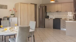 A modern kitchen with a dining area, featuring a refrigerator, cabinets, and a dining table set for two. - Premium Luxury Living Lefkada (Lefkada)