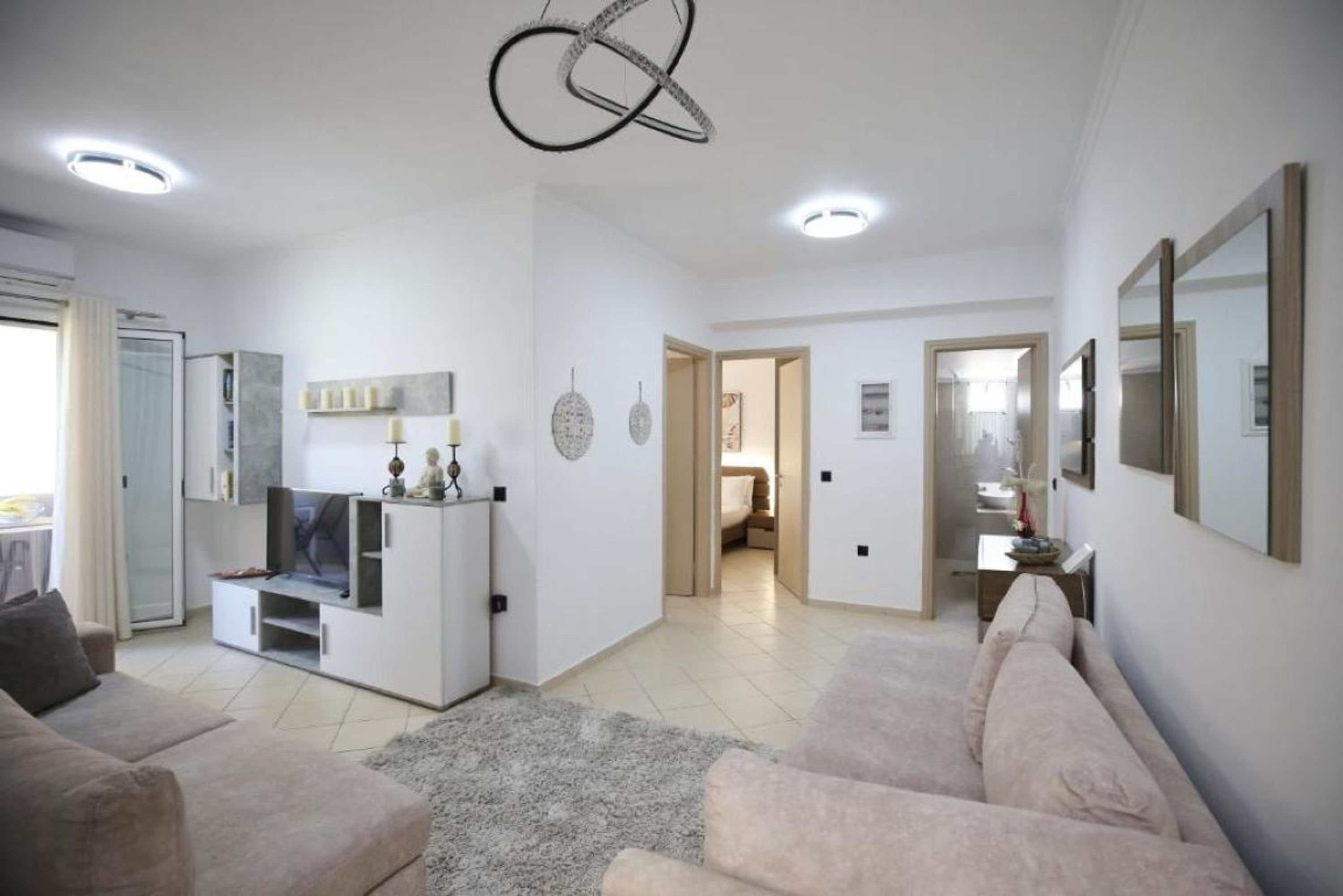 A spacious living area with a sofa, TV, and a modern ceiling light fixture.