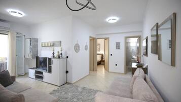 A spacious living area with a sofa, TV, and a modern ceiling light fixture.
