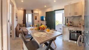A modern kitchen with a dining area, a flat-screen TV, and a large window. - Aetheria Luxury Living Lefkada (Lefkada)
