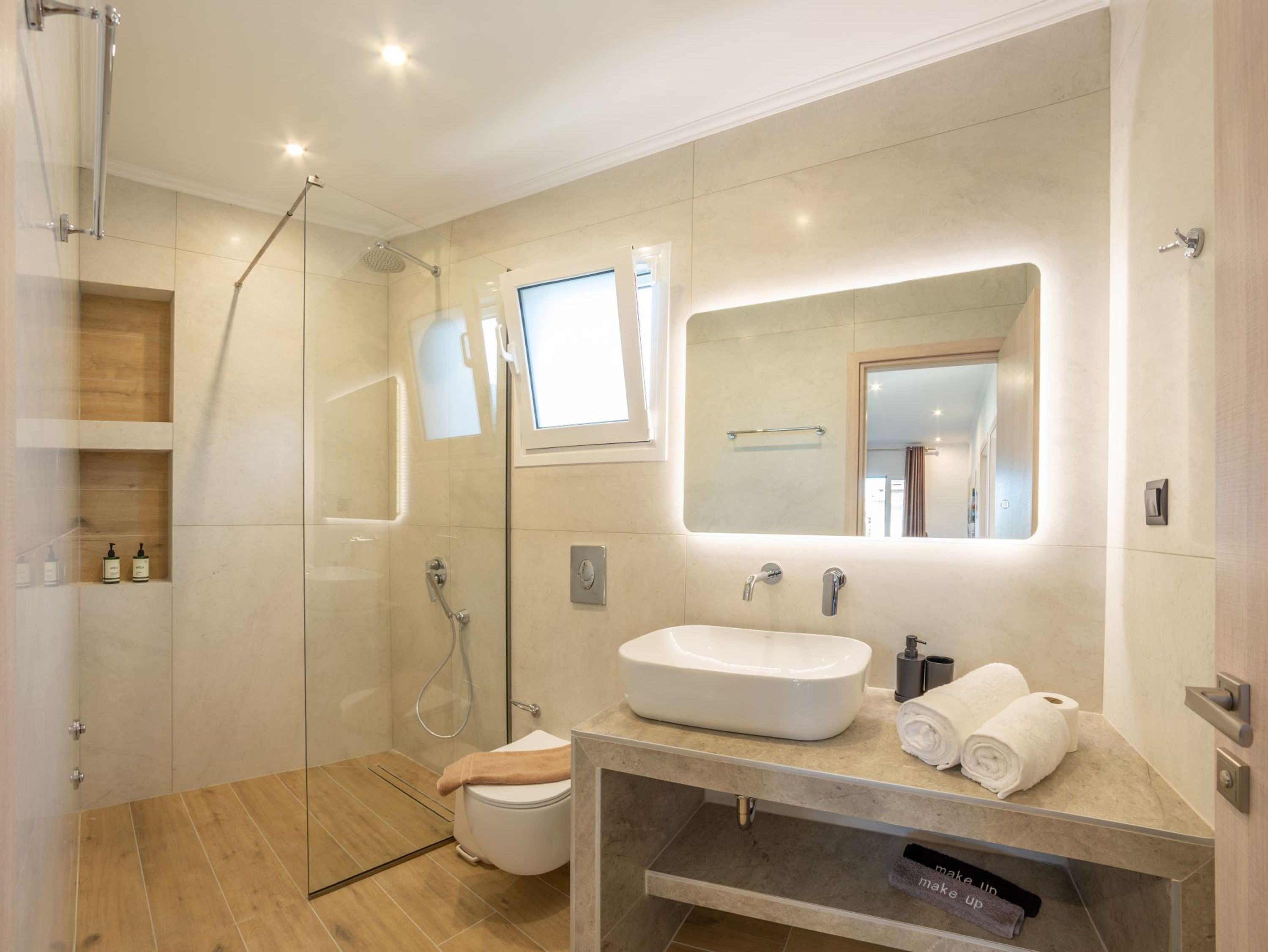A modern bathroom with a glass shower enclosure, a built-in sink, and a large mirror.