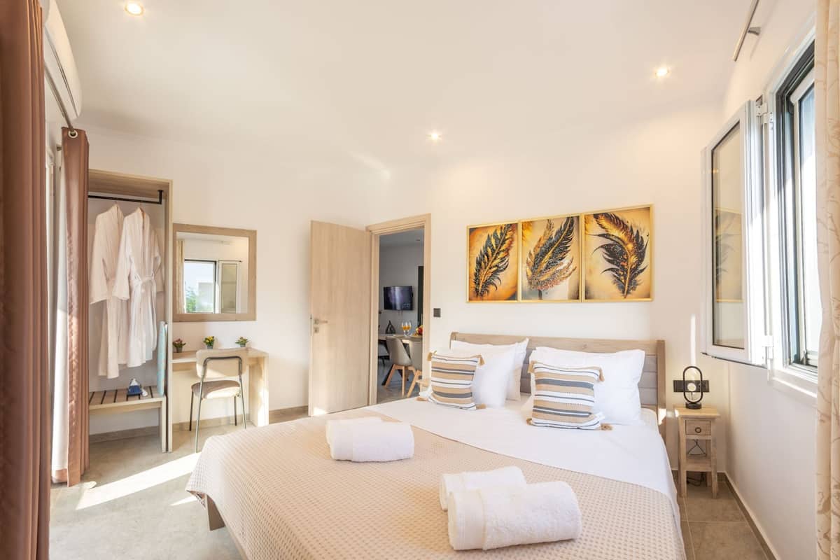 Una habitación de hotel con cama, escritorio, silla, armario y cuadros en la pared.