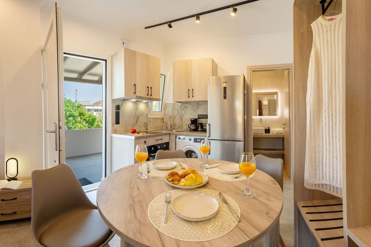 Una cocina moderna con armarios de madera, un refrigerador de acero inoxidable y una zona de comedor con una mesa redonda para dos.