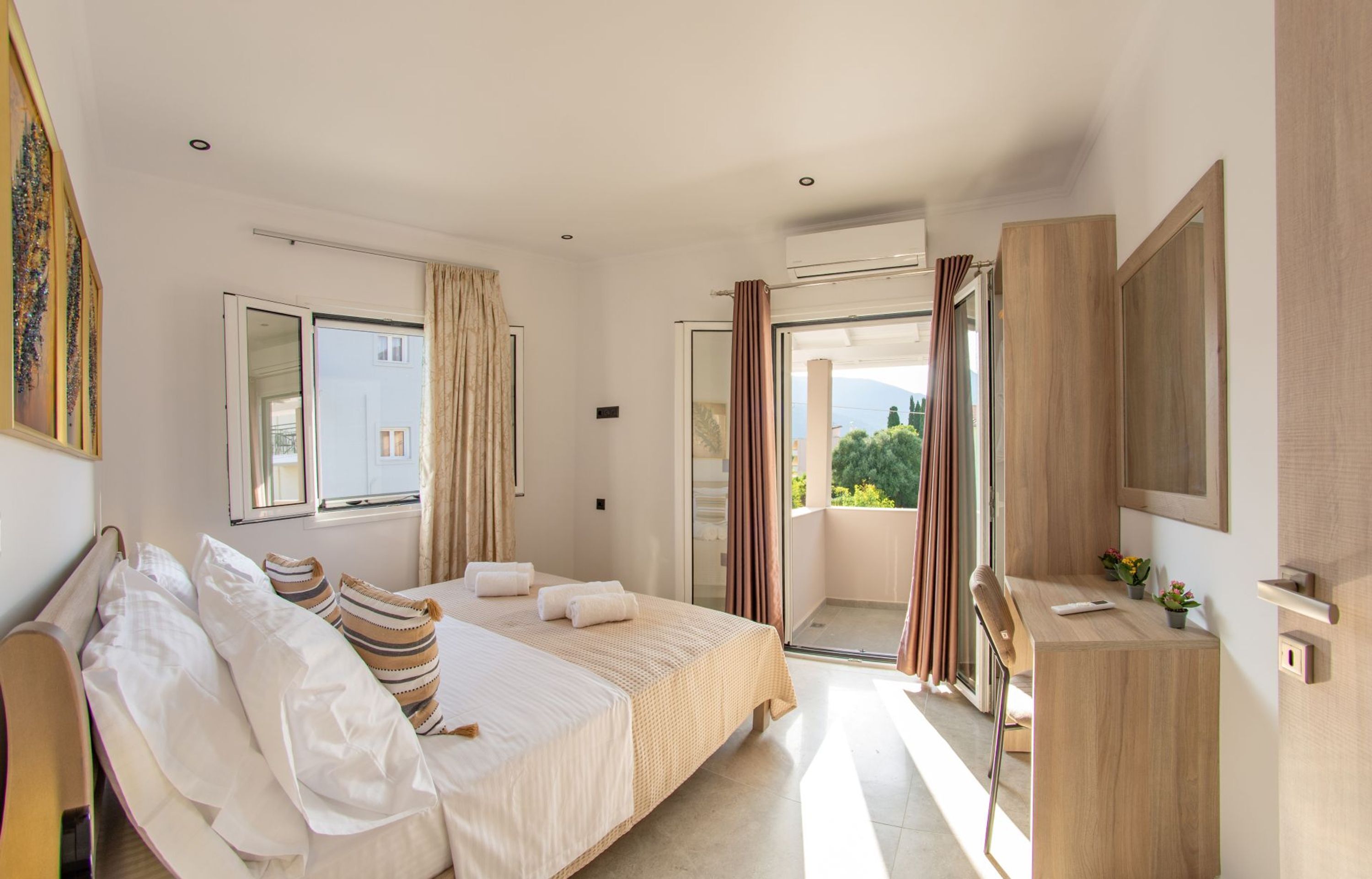 Ein Schlafzimmer mit Bett, Schreibtisch, Fernseher und einem Balkon.
