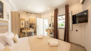 A hotel room with a bed, a dining area, a kitchen, and a TV.