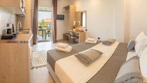 Ein modernes Hotelzimmer mit Bett, Schreibtisch, Stuhl, einer kleinen Küchenzeile und Bad.