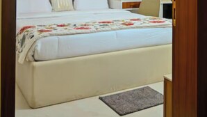 A bedroom with a bed, a ceiling fan, a painting, a bedside table, and a chair. - GGH Coastal Nest On The Beach (Brahmagiri)