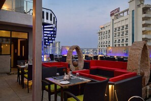 A rooftop restaurant with outdoor seating, a spiral staircase, and a view of the cityscape. - Divine Heritage Hotel (Jaipur)