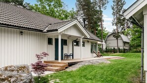 Una casa a un piano bianca con veranda coperta, un vialetto in pietra e un prato.