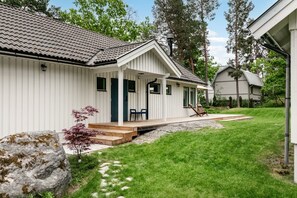 Ein weißes Einfamilienhaus mit überdachter Veranda, einem Kiesweg und einem Rasen.
