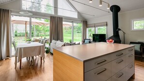 Un'ampia zona giorno con una grande isola in legno, un tavolo da pranzo e angolo cottura con piano cottura nero.