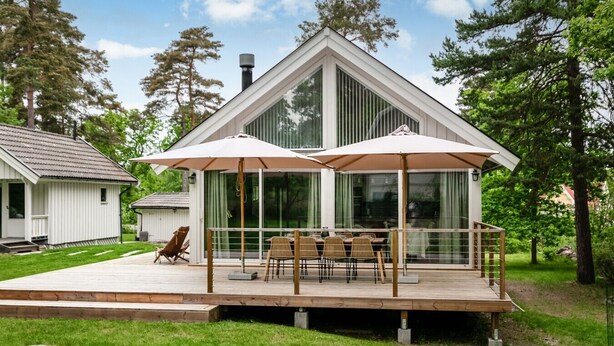 Una casa moderna con una terrazza, mobili da esterno e una zona patio coperta.
