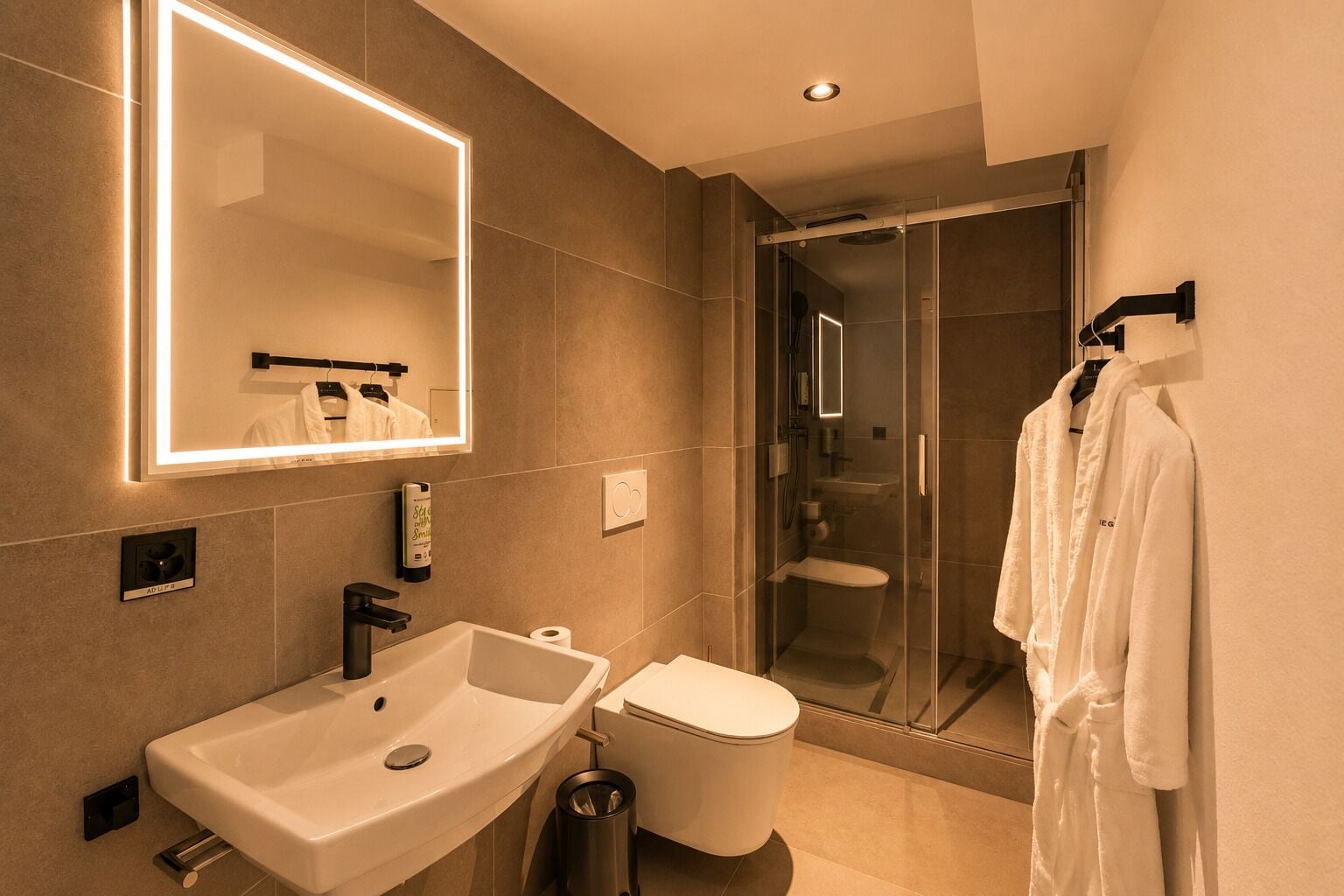 Een moderne badkamer met een grote spiegel, een wastafel, een toilet en een douche met glazen wanden.