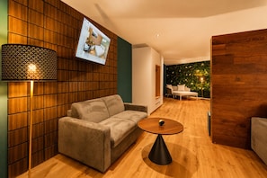 A modern living room with a sofa, a coffee table, and a wall-mounted TV.