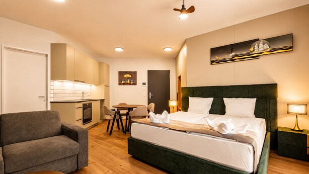 Habitación de hotel con cama, escritorio, silla, kitchenette y mesa de comedor.