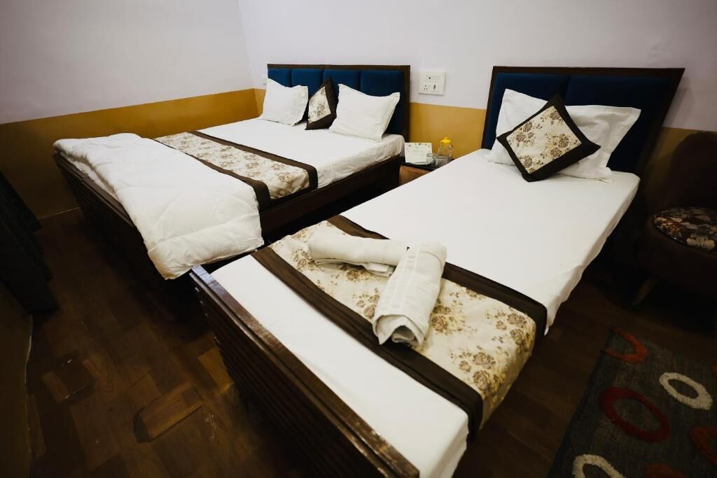 A hotel room with two single beds, each with a white bedspread and matching pillows.