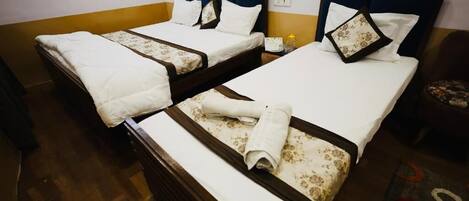 A hotel room with two single beds, each with a white bedspread and matching pillows.