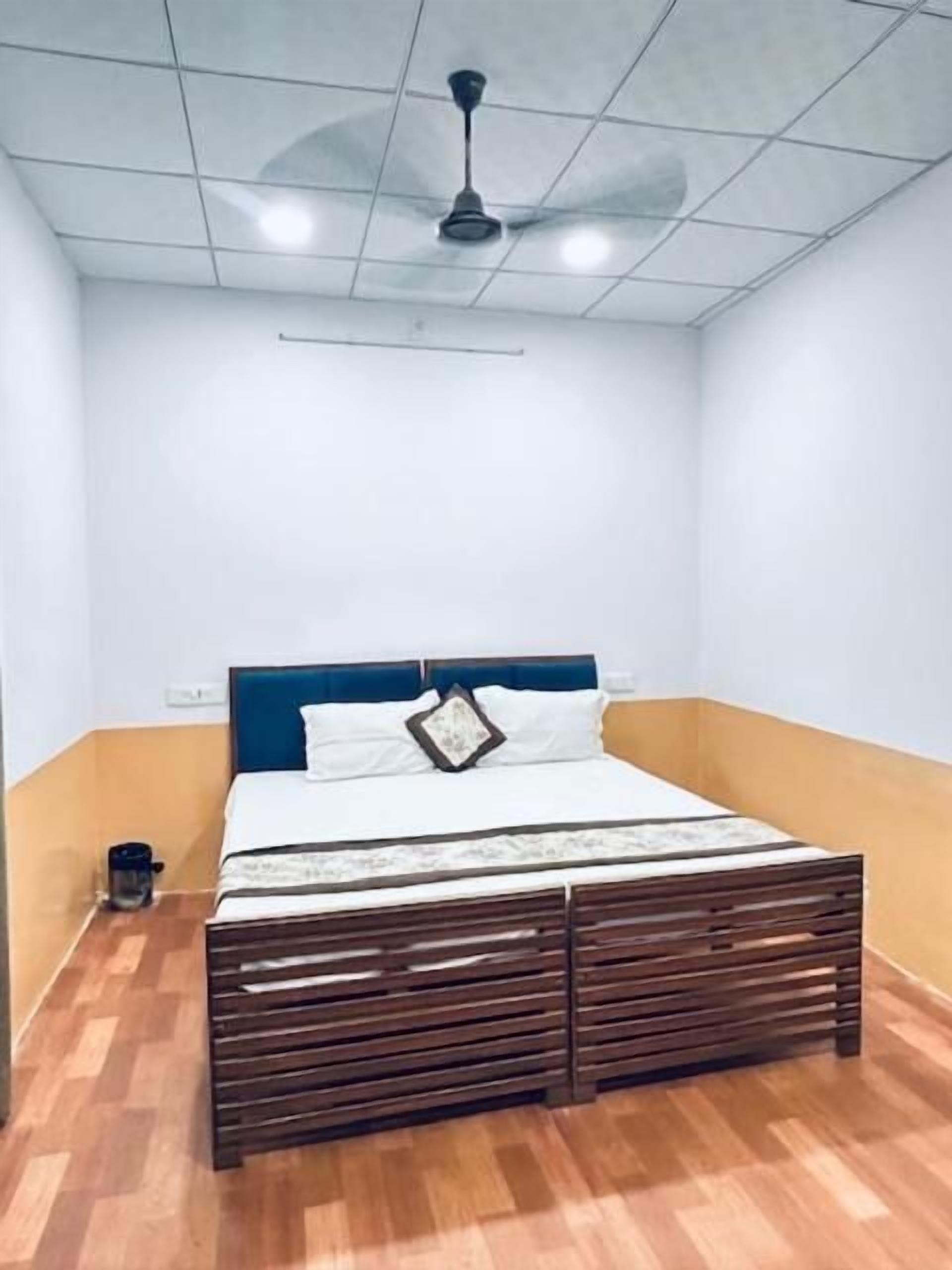A bedroom with a bed, a ceiling fan, and a wooden floor.