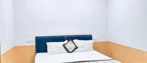 A bedroom with a bed, a ceiling fan, and a wooden floor.