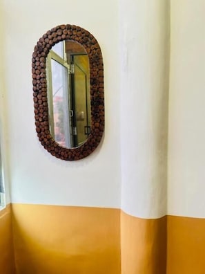 A wall with a circular mirror framed by a pattern of small, round objects.