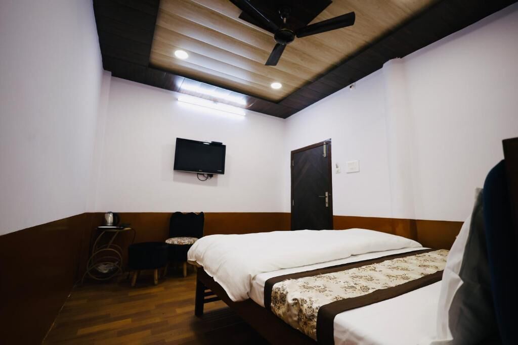Una habitación con cama, televisor montado en la pared, ventilador de techo y una puerta.