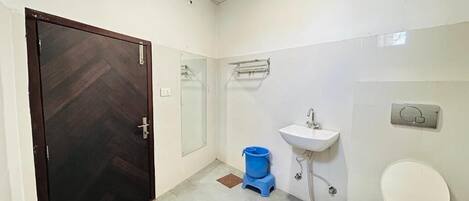 Un baño con inodoro, lavabo y un balde azul en el suelo.