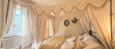 Une chambre à coucher avec un lit à baldaquin, un radiateur et une vue sur l’extérieur.