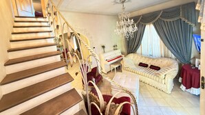 A grand staircase leading to a living area with a chandelier, a piano, and a sofa. - Charming Tuscan Home - Near Pisa, Volterra & Wine Tours (Capannoli)