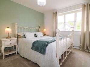 A bedroom with a bed, nightstands, a window, and a view of the outside. - The Haven (Nottingham)