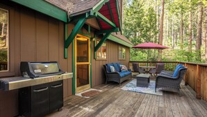 A wooden deck with a grill, wicker furniture, and a red umbrella. - Kennedy Mountain Chalet - AC & Pool Access! (Arnold)