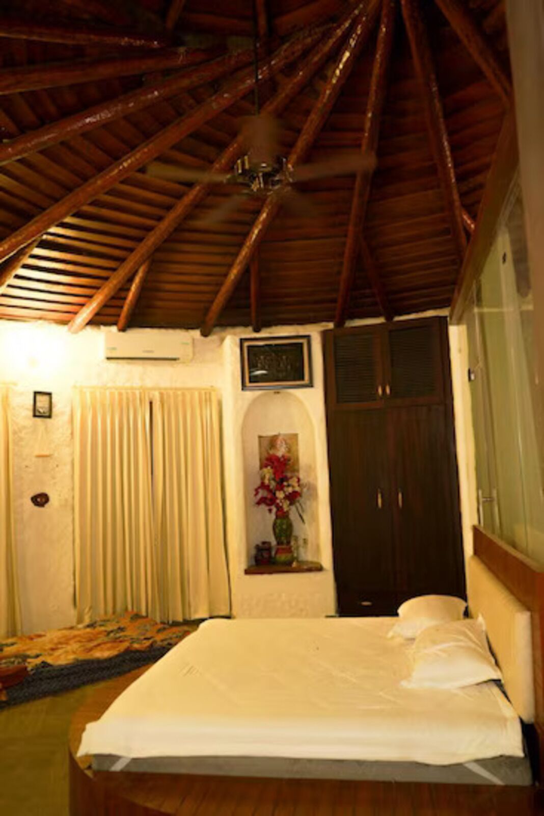 A bedroom with a wooden ceiling, a bed, a window, and a door.