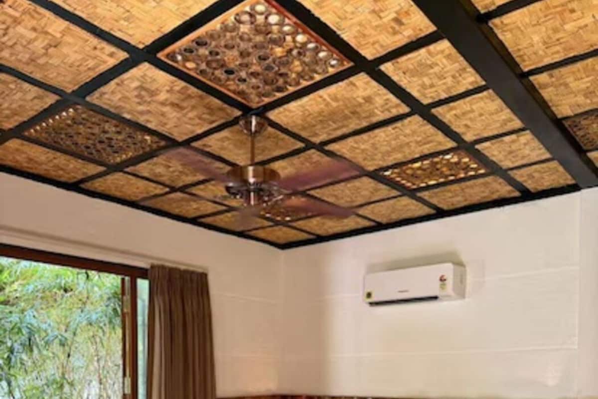 A bedroom with a large bed, wooden headboard, and a ceiling with a geometric pattern.