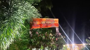 A well-lit outdoor area with a sign, potted plants, and a stone pathway. - Corbett Cabana Farm (Haldwani)
