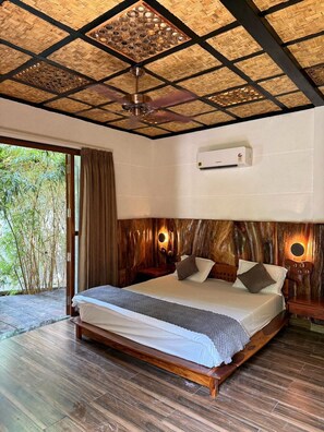 A bedroom with a large bed, wooden headboard, ceiling fan, and an air conditioning unit.
