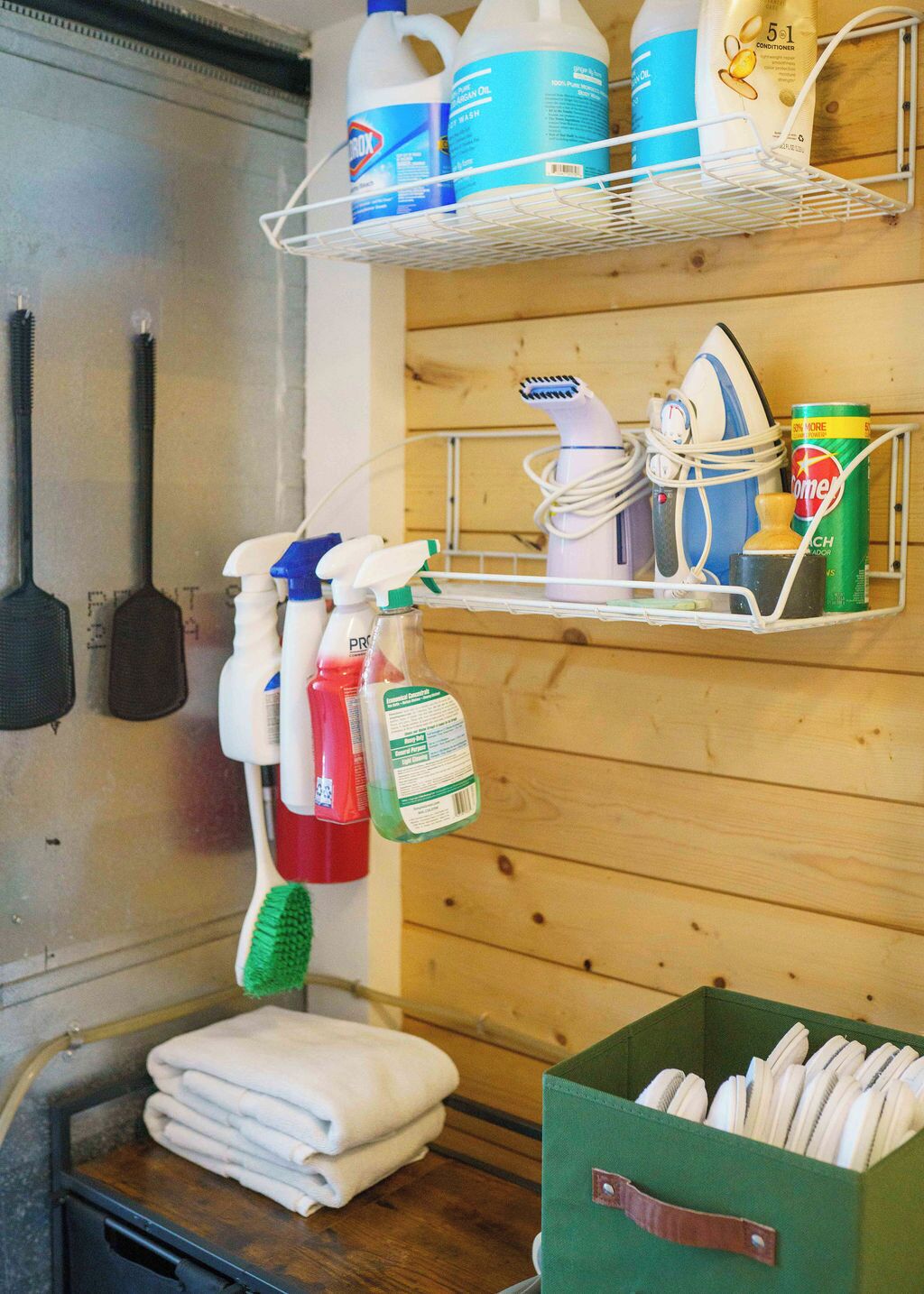 Un área de cocina con un estante que contiene productos de limpieza, un secador de pelo y una lata de refresco.