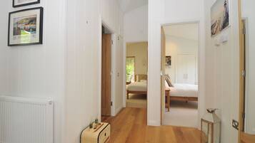 A hallway leading to a bedroom with a bed, a wooden chest, and a radiator.