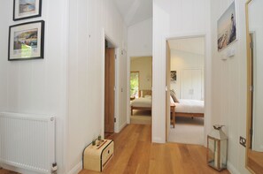 A hallway leading to a bedroom with a bed, a wooden chest, and a radiator. - 11 Water's Edge (Looe)