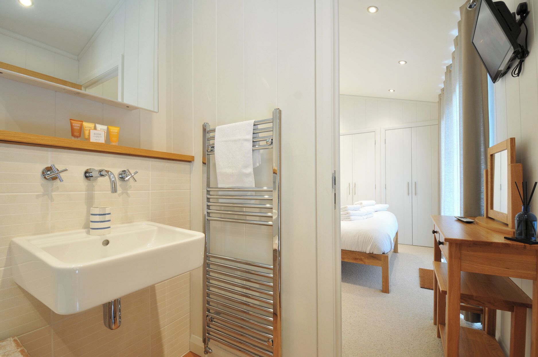 Une salle de bain moderne équipée d’un lavabo, d’un porte-serviettes et d’une douche.